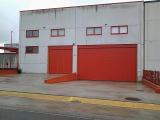 Puerta Industrial Puerta Seccional Hörmann con puerta peatonal incorporada y Puerta Seccional a juego en color rojo